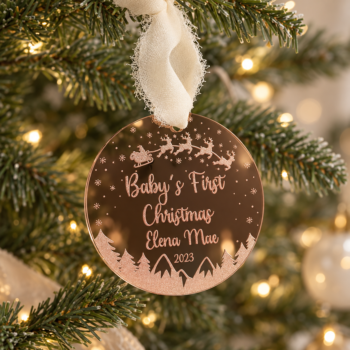 Personalized rose gold Baby’s First Christmas acrylic ornament hanging on a Christmas tree