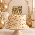 In My Golden Birthday Era gold mirrored acrylic cake topper displayed on an ivory and gold birthday cake