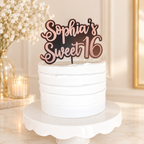 Rose gold personalized Sweet 16 acrylic topper on a white cake