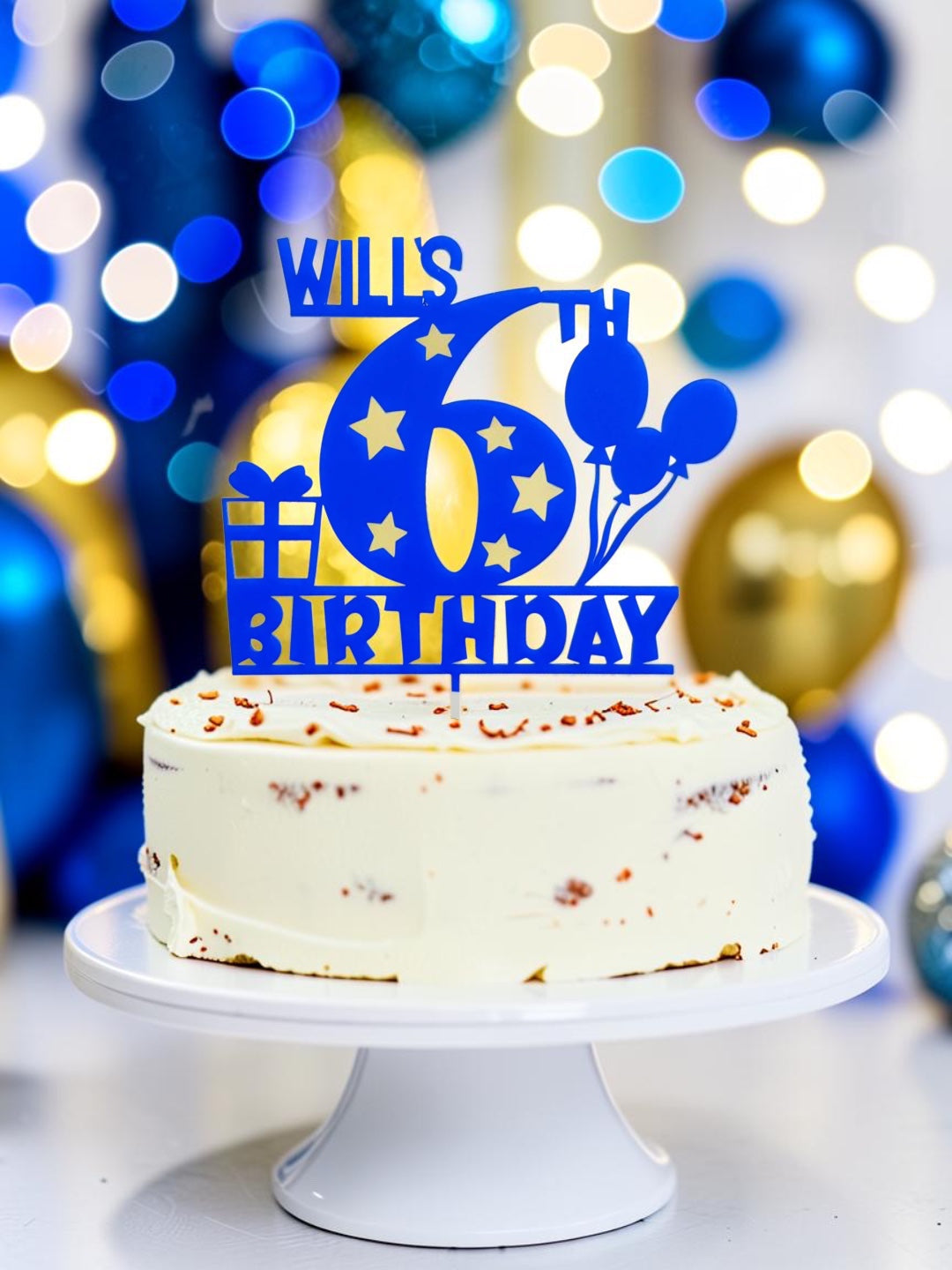 Blue personalized name and age birthday cake topper with stars and balloons displayed on a white cake