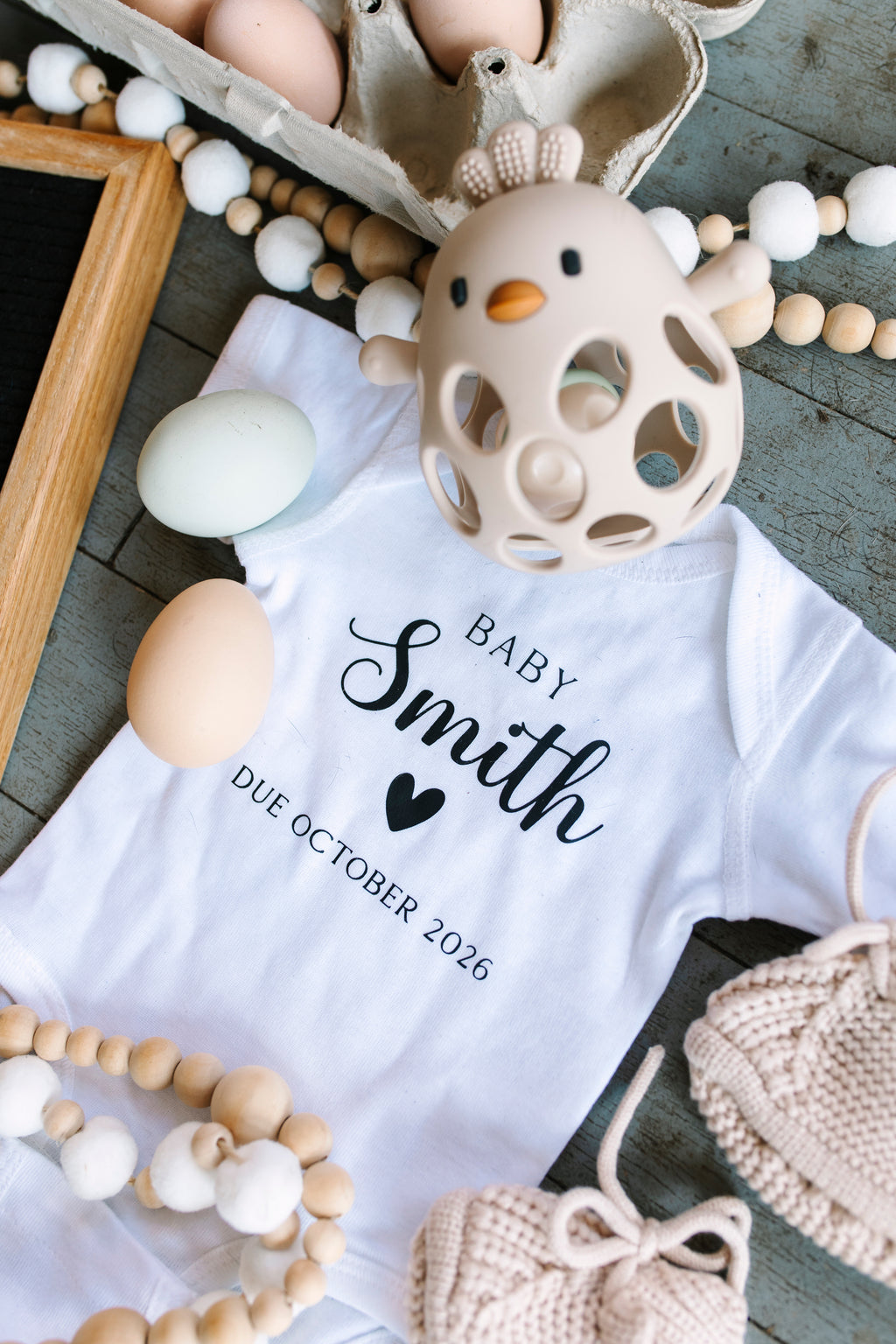 Baby Smith personalized pregnancy announcement bodysuit in styled flat lay