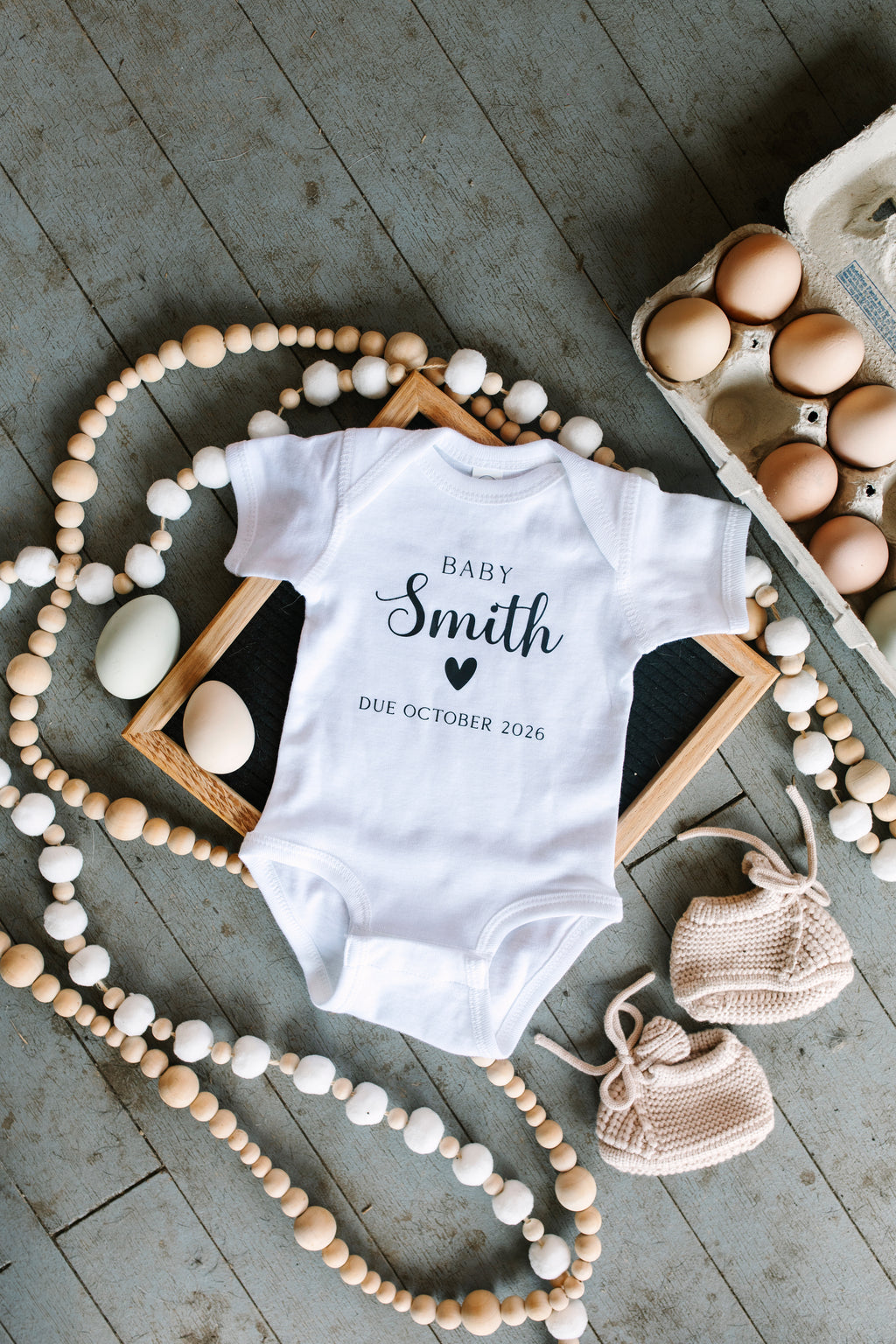 Close-up of personalized baby bodysuit with last name and due date 