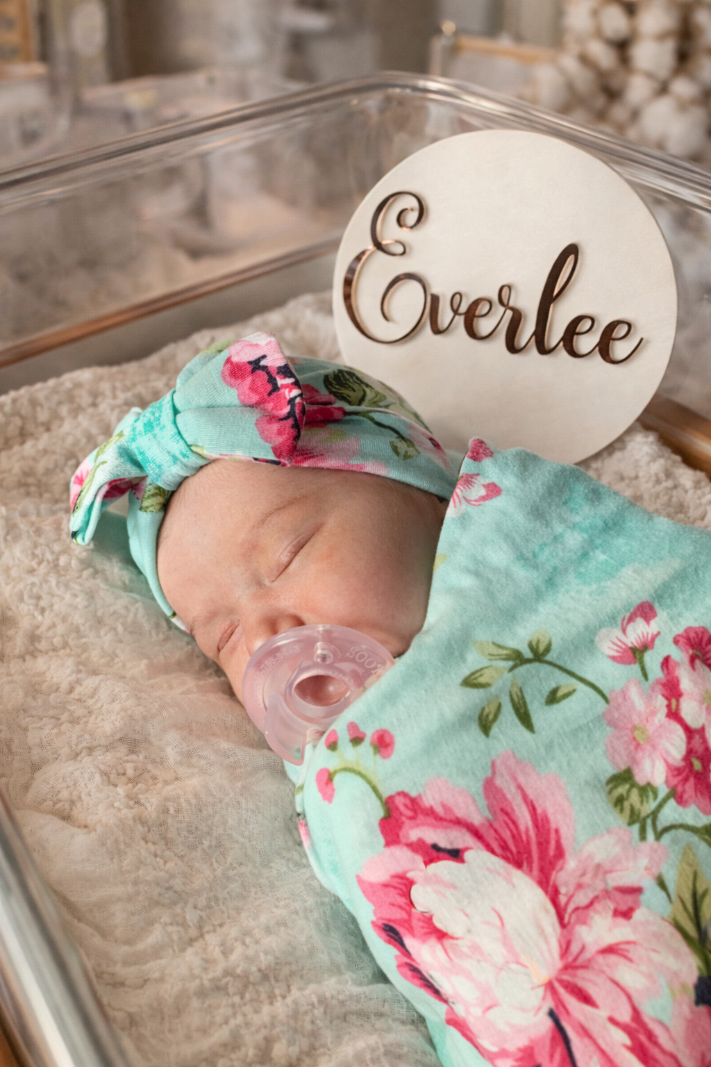 Newborn baby in floral outfit with 'Everlee' sign