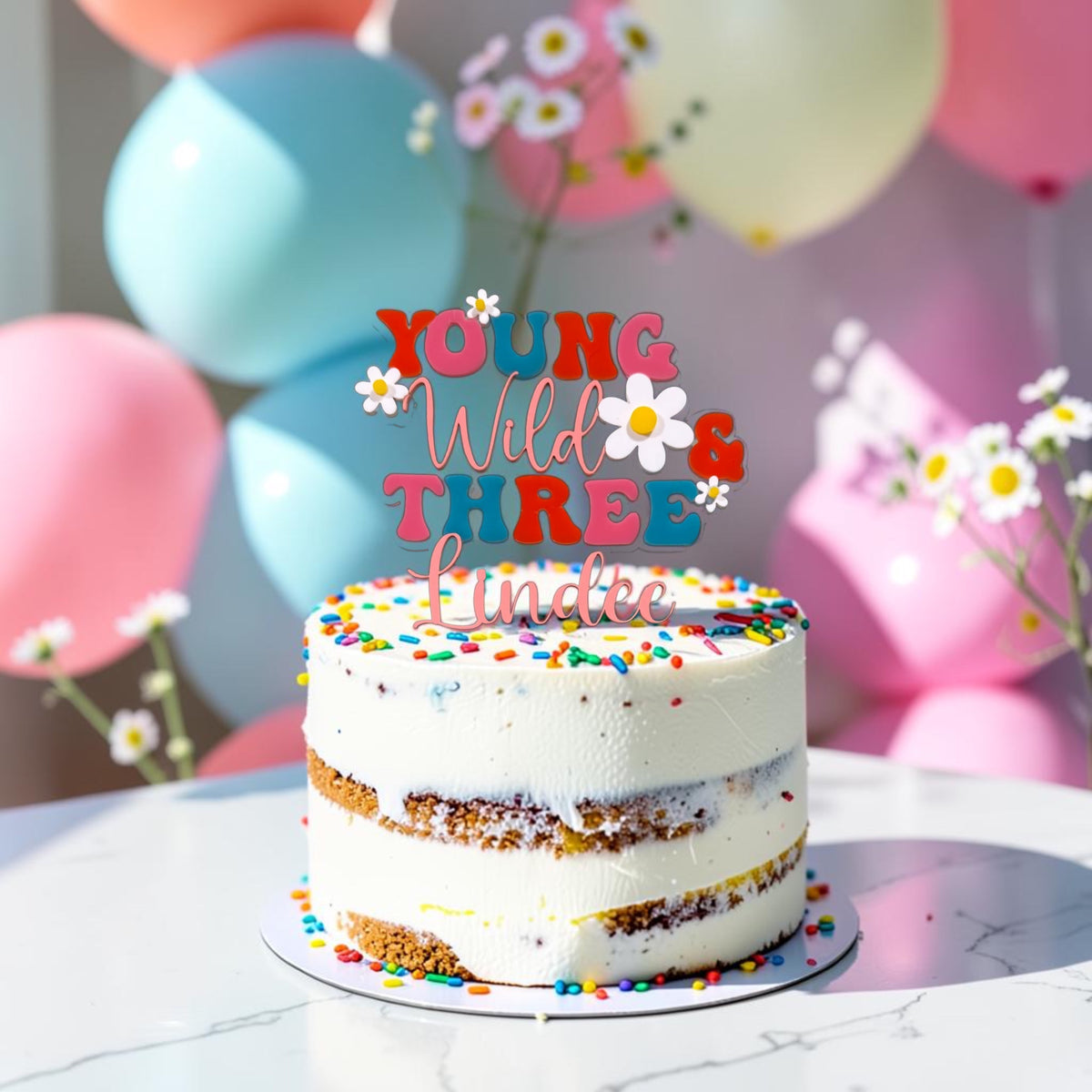 Personalized Young Wild and Three acrylic cake topper displayed on a colorful third birthday cak